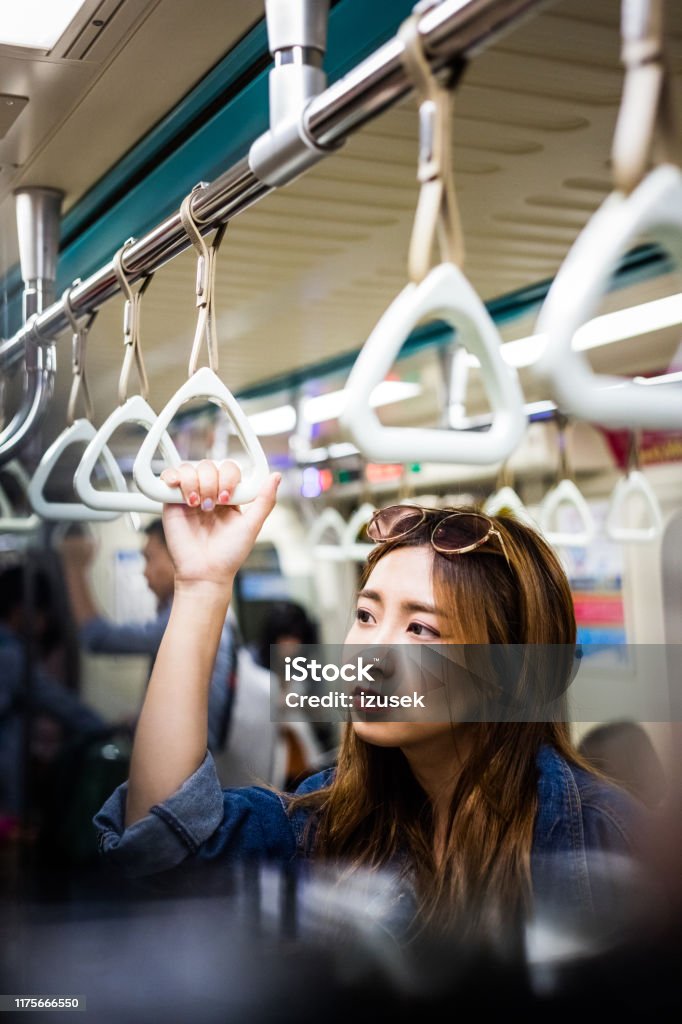 Thoughtful woman traveling in subway train Thoughtful woman traveling in subway train. Young female is holding handle during journey. She is looking away. 20-24 Years Stock Photo