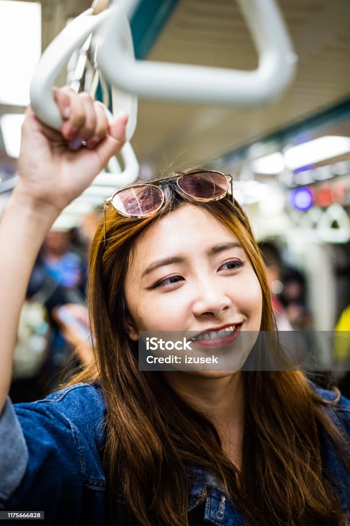 Young women looking away in subway train Close-up of young women looking away in subway train. Thoughtful female is traveling in public transport. She is smiling. 20-24 Years Stock Photo