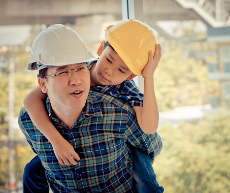 Builder father is carrying his son on his back for father son success bond and togetherness concept