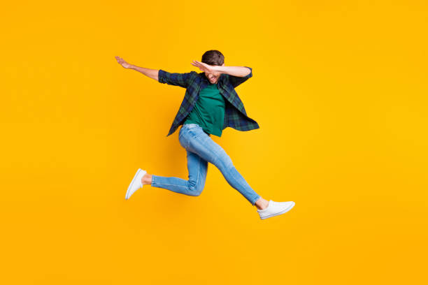 foto de corpo inteiro de alegre conteúdo sonho funky homem saltar divirta-se dança como verdadeiro clubber desfrutar férias de verão desgaste jeans sapatilhas verificado camisa verde isolada sobre fundo de cor amarela - dab dança - fotografias e filmes do acervo