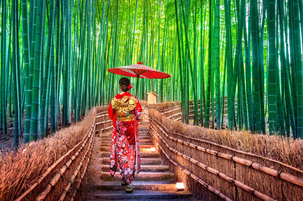 竹林。アジアの女性は、日本の京都で竹林で日本の伝統的な着物を着ています。