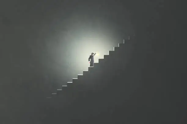 Photo of man with lamp rising stairs in the darkness