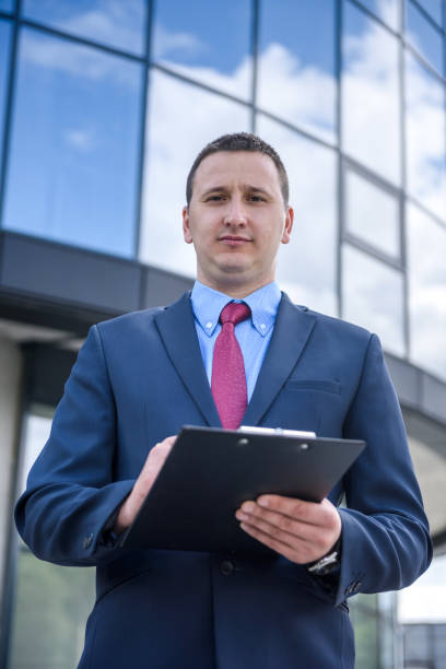 istock Man in suit with clipboard standing outdoors 1175670089
