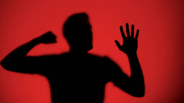 istock Male silhouette knocking on glass, red light background, warfare concept 1175670099