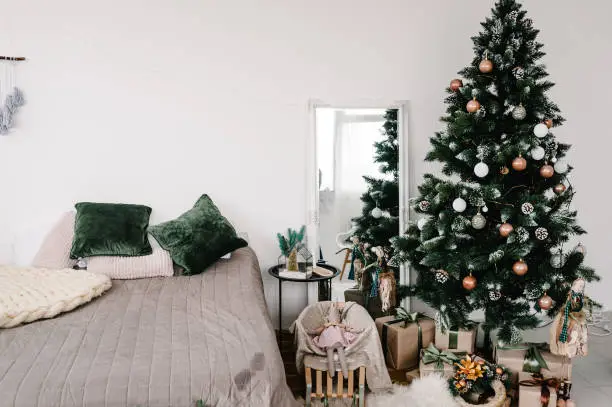 Decorated Christmas interior. Christmas tree with gifts boxes in a white room. Fir-tree decorated with garlands. Decor. Happy New Year and Merry Christmas. The concept of winter holiday.
