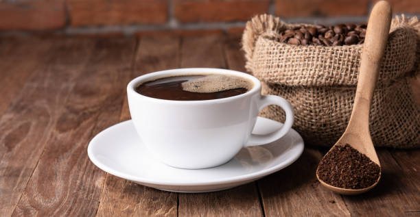 istock Coffee cup,coffee ground and coffee beans in burlap on wood table with brick wall background 1175671377