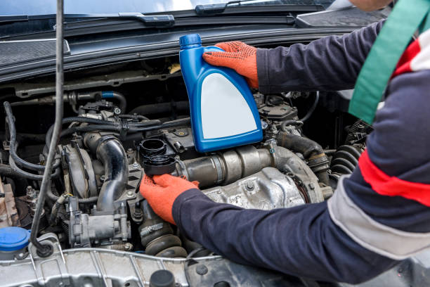 istock Mechanic holding bottles with oil near car engine 1175673653