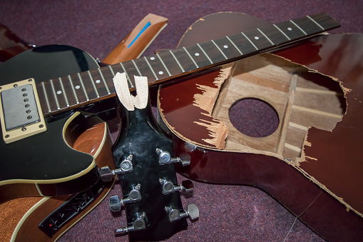 Broken guitars. Pile of smashed electric and acoustic guitar pieces. Frustrated guitarist smashed instrument parts ready for burning or repair.