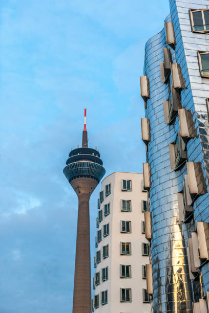 Dusseldorf, Germany - December 19, 2012: facade of contemporary office buildings at the Media Harbor, Medienhafen, at Neuer Zollhof designed by architect Frank O. Gehry and Rheinturm Tower at sunset in Dusseldorf Germany