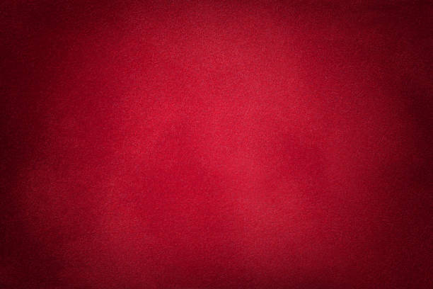 Dark red matte background of suede fabric, closeup. Dark red matte background of suede fabric, closeup. Velvet texture of seamless wine leather. Felt material macro with vignette. garnet stock pictures, royalty-free photos & images