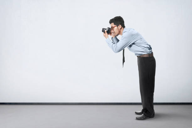 Asian businessman take a picture with his camera over white wall background