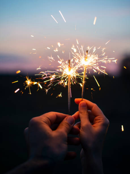 istock Two hands holding sparkling fireworks to the sky at twilight a 1175678778