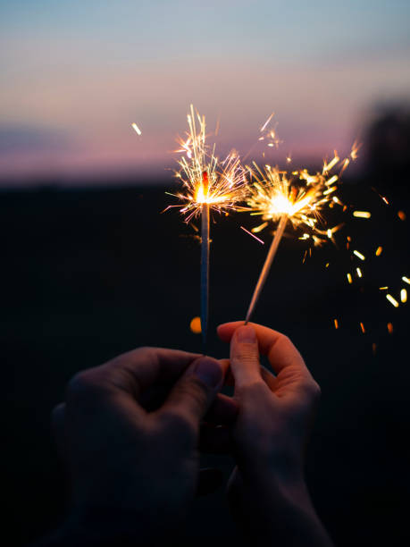 istock Two hands holding sparkling fireworks to the sky at twilight a 1175678779