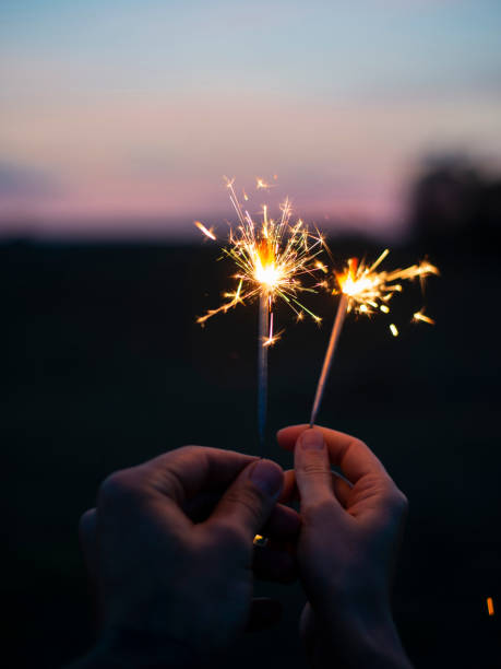 istock Two hands holding sparkling fireworks to the sky at twilight a 1175678915