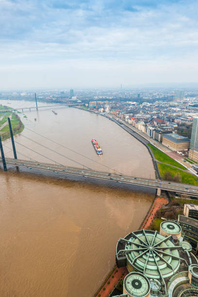 river Rhine and Düsseldorf, arial view. Barge heavily loaded with coal is passing the bridge Rheinkniebrücke.