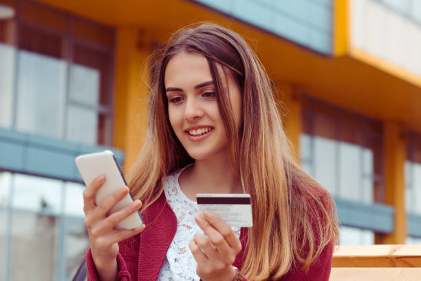 istock Smiling woman with phone and card 1175681571