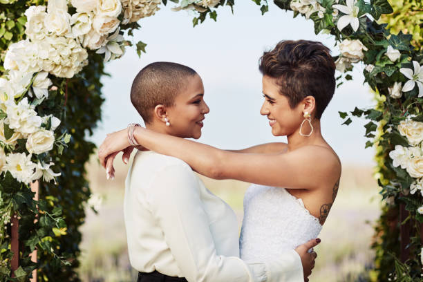 I couldn't have been anyone else's wife Cropped shot of an affectionate young lesbian couple standing with their arms around each other on their wedding day wedding reception photos stock pictures, royalty-free photos & images