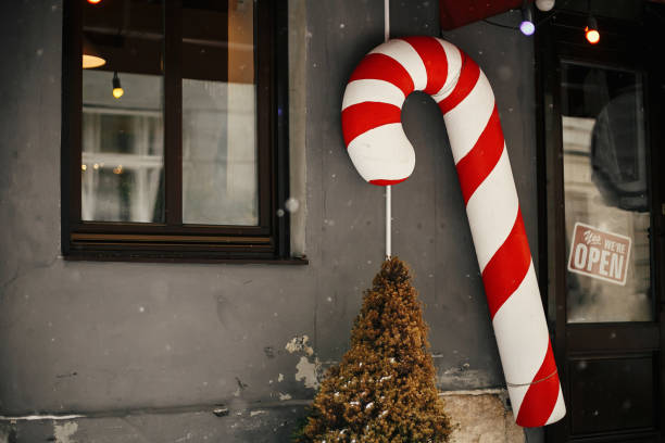 décor de rue de noel. jouet élégant de canne de sucrerie de noel à l'avant de magasin au marché de vacances dans la rue de ville. espace pour le texte. décor festif - window display toy store store christmas photos et images de collection