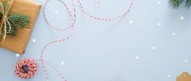 istock Christmas flatlay composition on blue background. Top view gift box, fir tree branch, rope, glitter confetti stars. Xmas or New Year banner mockup with copy space for text. 1175684915