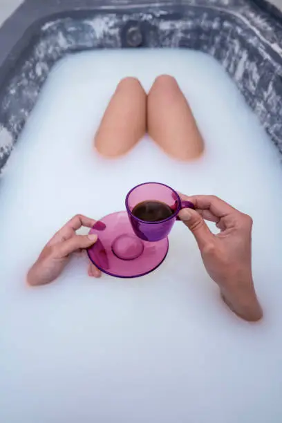 woman hand drinking coffee in pink cup at milk bathtub