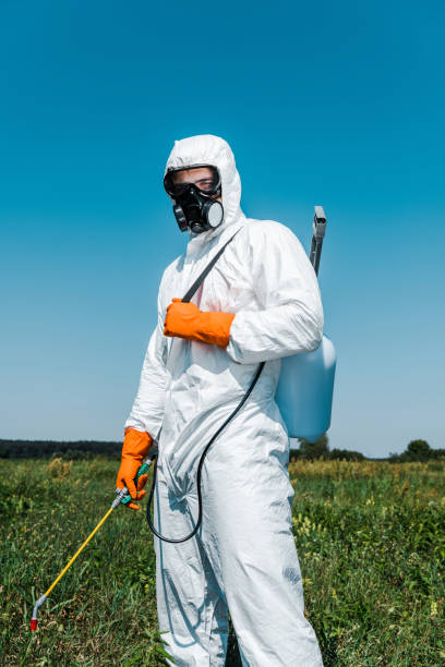 istock exterminator in white uniform and latex gloves holding spray against sky 1175685955