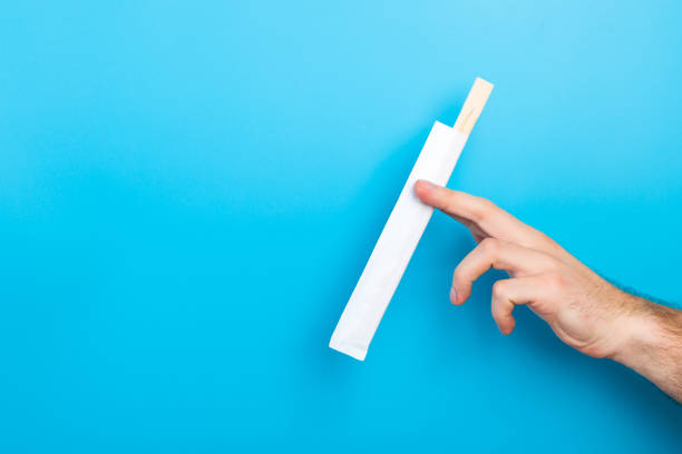 istock Man's hand holding chopsticks in a pack on blue background. Chinese food concept with empty space for your design 1175686000