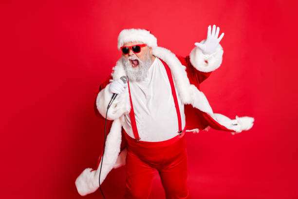 portrait of cool funny fat overweight santa claus with big belly sing song on christmas party wear style stylish trendy eyeglasses eyewear hat isolated over red background - image singing fun vacations imagens e fotografias de stock