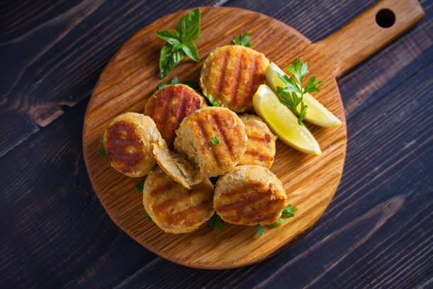 pasteles de pescado con limón y hierbas. empanadas de pescado en tabla de madera - galette fotografías e imágenes de stock