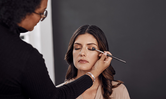 Cropped shot of a woman having her makeup done by a makeup artist