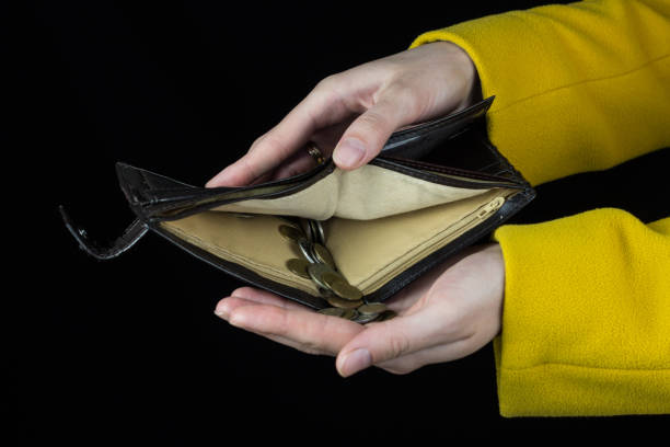 istock Female hands hold a purse from which poured coins, a black background 1175688731