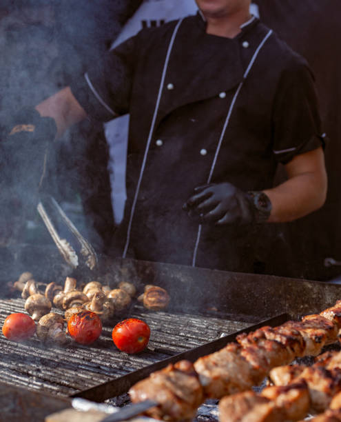 istock Brazier grills meat and vegetables by turning them with iron tongs 1175689100