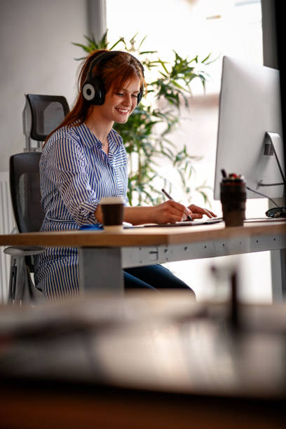 Woman graphic designer working in office with headphones