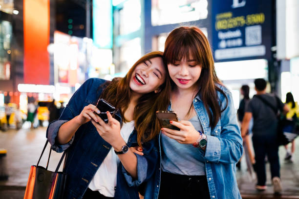istock Cheerful female friends using smart phone in city 1175691364