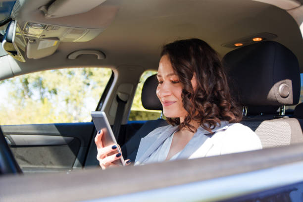istock Smiling happy woman browsing the internet on a smart phone while driving a car 1175692180