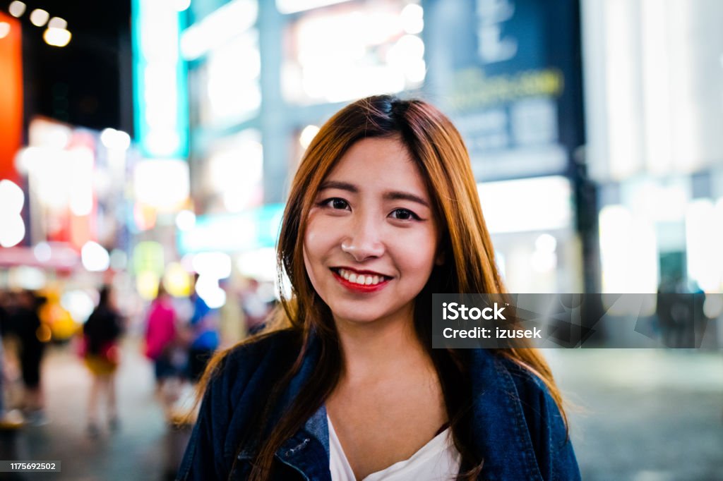 Portrait of smiling young woman in city at night Portrait of smiling young woman in city. Close-up of beautiful female is standing on street at night. She is having brown hair. 20-24 Years Stock Photo