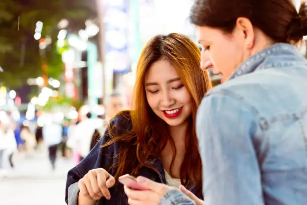 Photo of Smiling woman assisting tourist using mobile phone