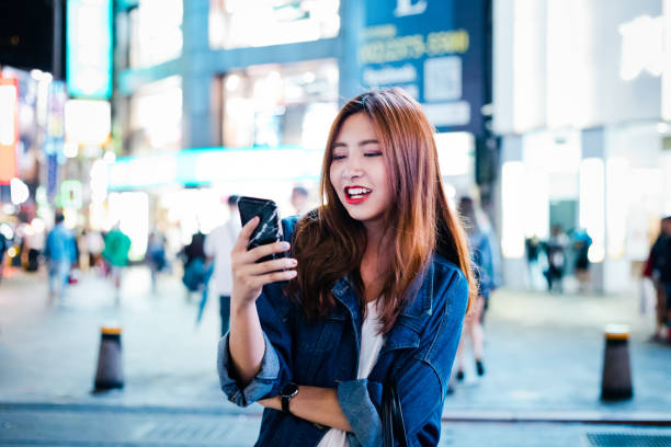 istock Smiling woman using smart phone in city at night 1175692750