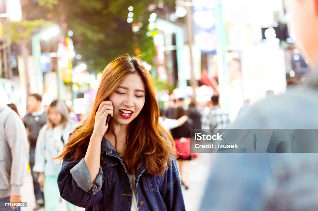 Woman talking on mobile phone in city at night Young woman talking on mobile phone while walking on street. Beautiful female is having long brown hair. She is in city at night. 20-24 Years Stock Photo