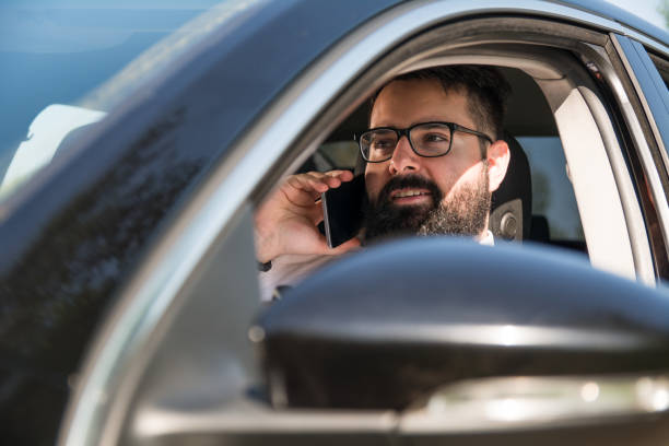 istock Close up of smiling bearded man using smart phone while driving his car 1175693741