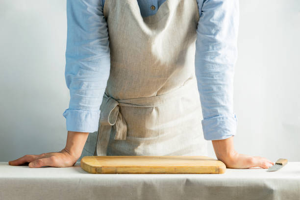 istock Female cook in cotton apron at the kitchen table with cutting board. Rustic natural style. Kinfolk concept. Copy space. 1175695668