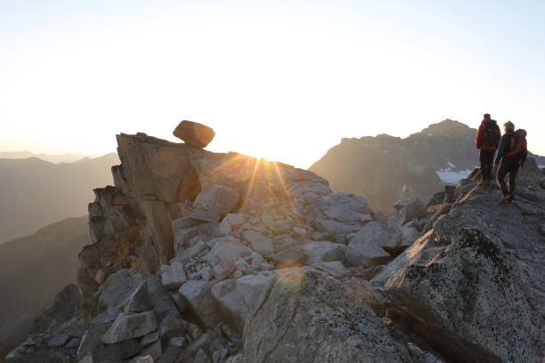 Male hikers ascend mountain ridge, sunrise They look off to distant scene upward mobility stock pictures, royalty-free photos & images