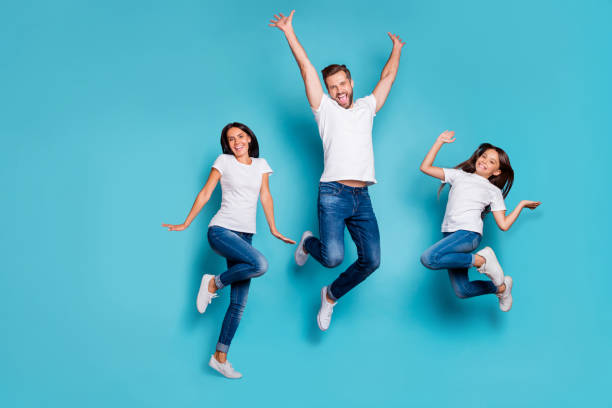 Full length body size photo of jumping enjoying nice glad family cute wearing white t-shirts jeans denim while isolated with blue background Full length body size photo of jumping enjoying nice glad family cute, wearing white t-shirts jeans denim while isolated with blue background fashionable dad stock pictures, royalty-free photos & images