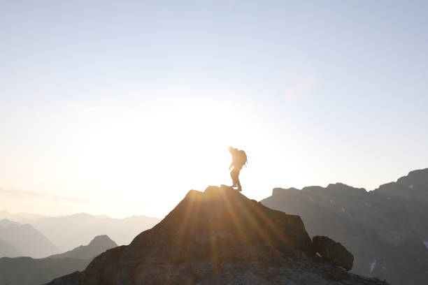 istock Male hiker ascends to mountain summit, sunrise 1175699091