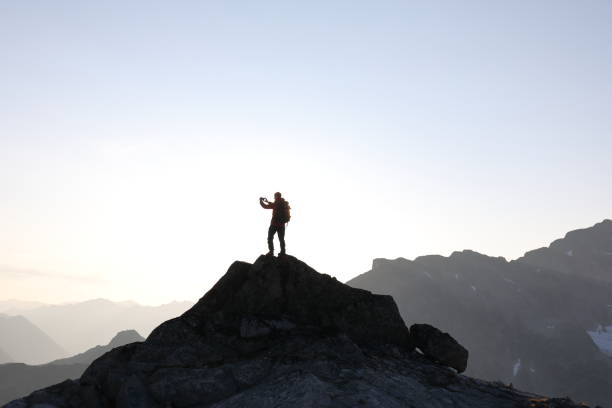 istock Male hiker ascends to mountain summit, sunrise 1175699109