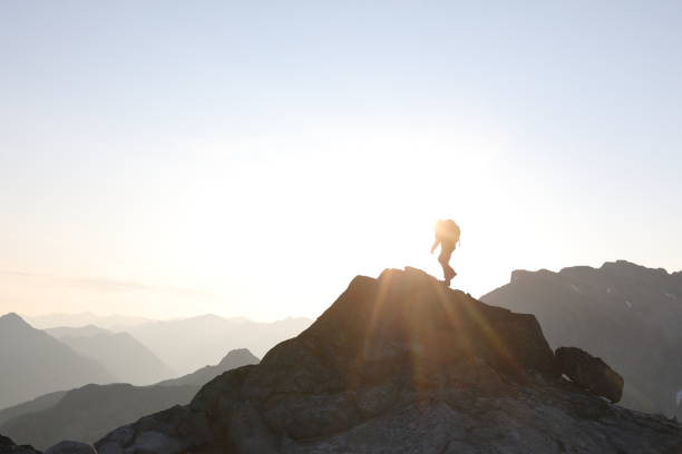 istock Male hiker ascends to mountain summit, sunrise 1175699151