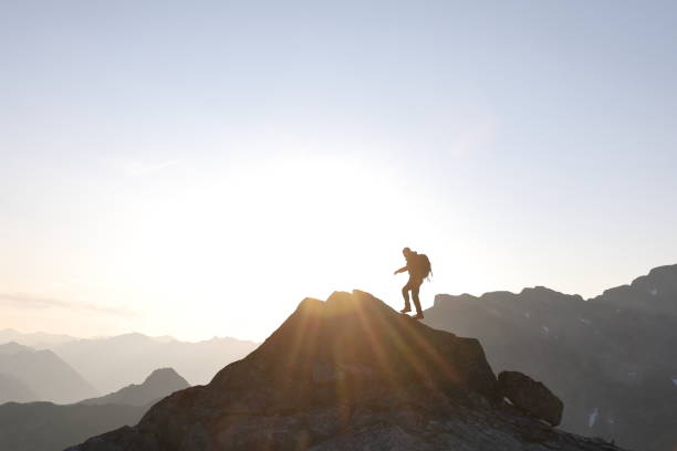istock Male hiker ascends to mountain summit, sunrise 1175699152
