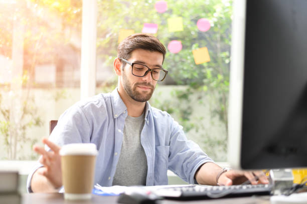 istock Home office A young man sitting at a computer screen at home with a cup of coffee. 1175699158