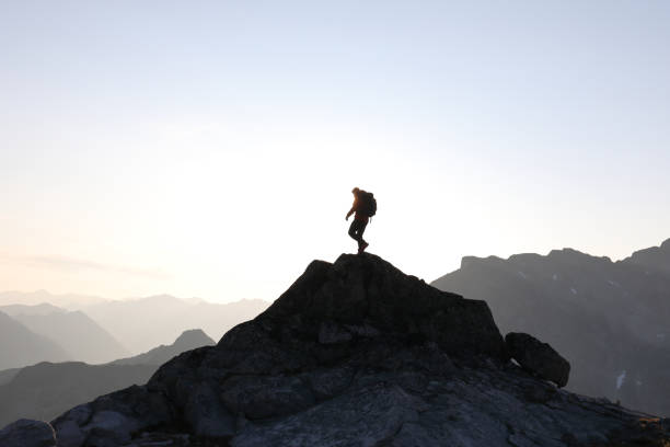 istock Male hiker ascends to mountain summit, sunrise 1175699171