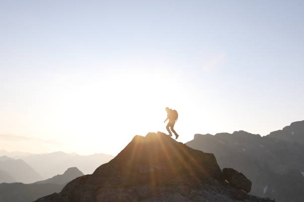 istock Male hiker ascends to mountain summit, sunrise 1175699196