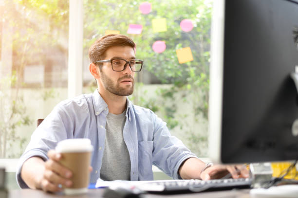 istock Home office A young man sitting at a computer screen at home with a cup of coffee. 1175699287